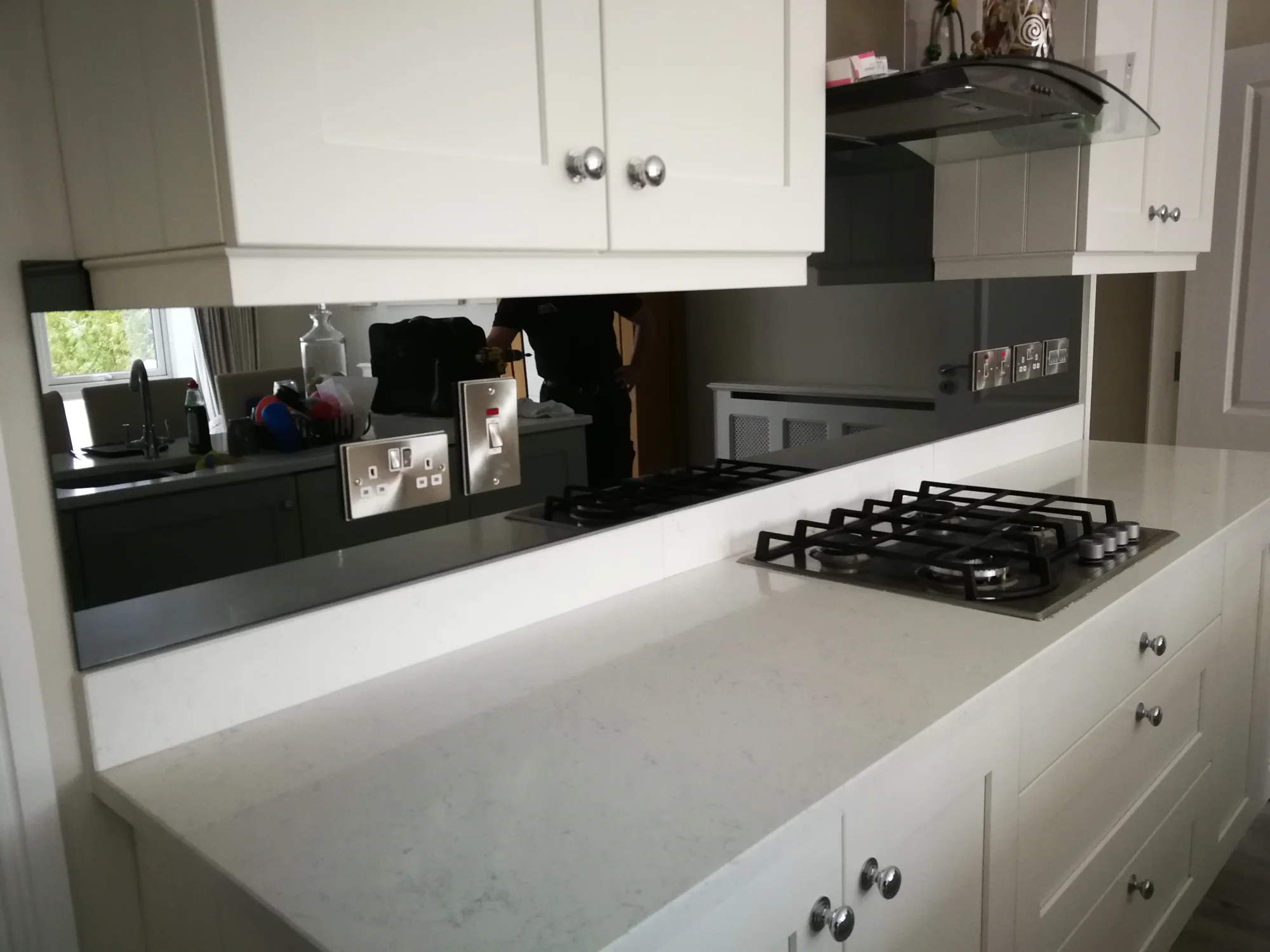 Black glass splashback fitted around a white kitchen